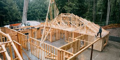 Wooden house frame under construction in forest.