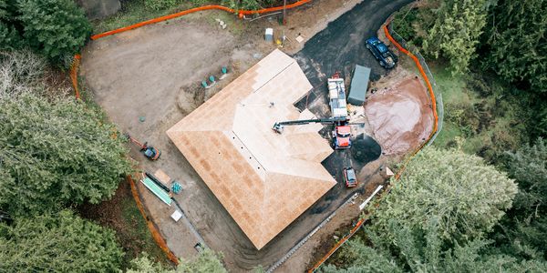 Aerial view of a house under construction surrounded by trees.