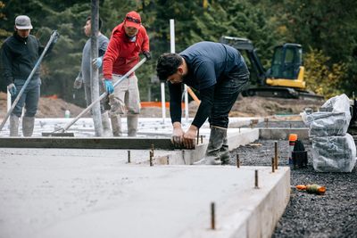 Workers smoothing freshly poured concrete on a construction site.