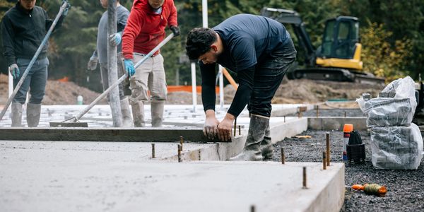 Workers smoothing and measuring concrete slab.