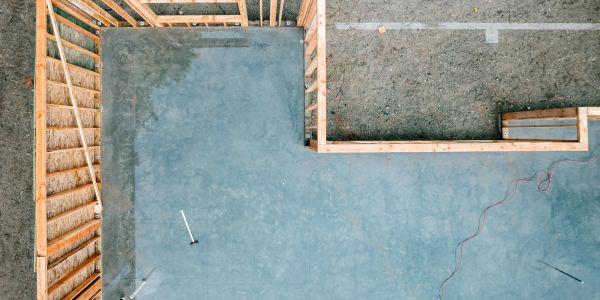 Aerial view of a concrete foundation and wooden framing at a construction site.