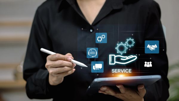 Person using tablet with digital service icons floating above.