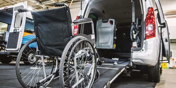 Wheelchair in front of a van with a ramp.