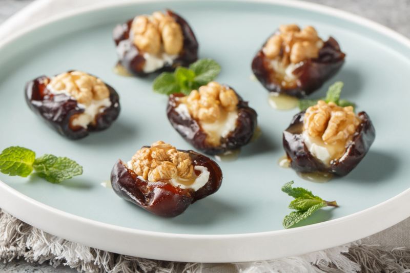 Honey walnut Cream Cheese Stuffed Dates in a porcelain plate closeup on the table. Horizontal