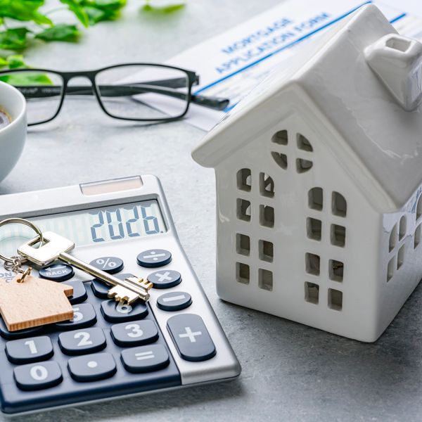 Calculator, house model, and keys representing mortgage planning.