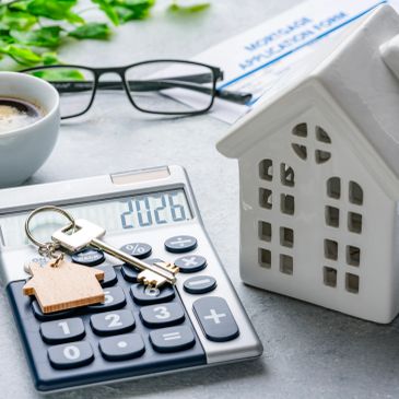 Calculator with house keys and model home symbolizing mortgage or home finance.