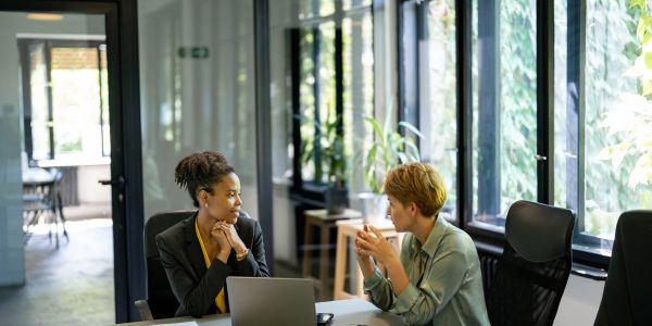 Two women in a meeting in a bright office.