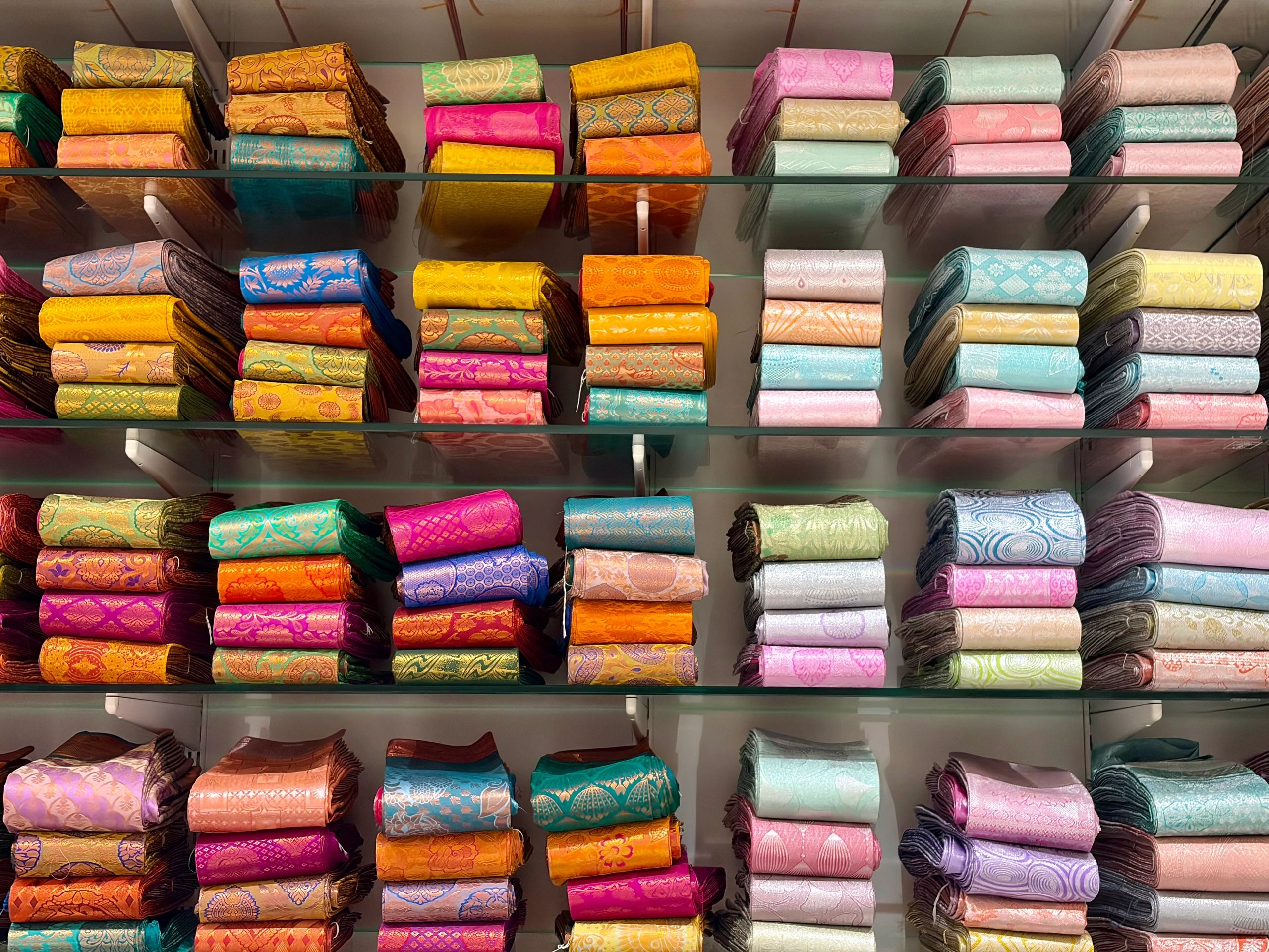 Colorful patterned folded fabrics stacked on shelves.