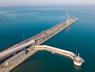 A long pier extending into calm blue waters under a clear sky.