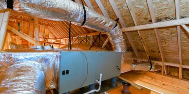 HVAC system installed in a wooden attic space with insulated ductwork.
