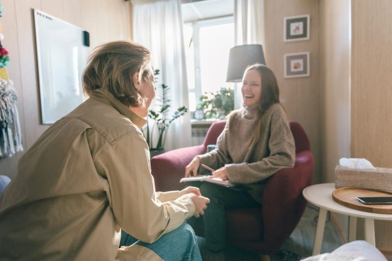 A relaxed counseling moment where therapist and client laugh together during a one-on-one session, highlighting trust, emotional connection, and a supportive therapeutic environment.