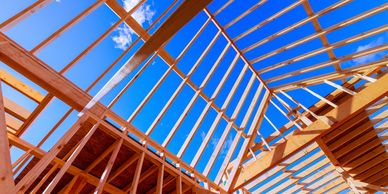 Wooden frame structure of a building under construction against a clear blue sky.