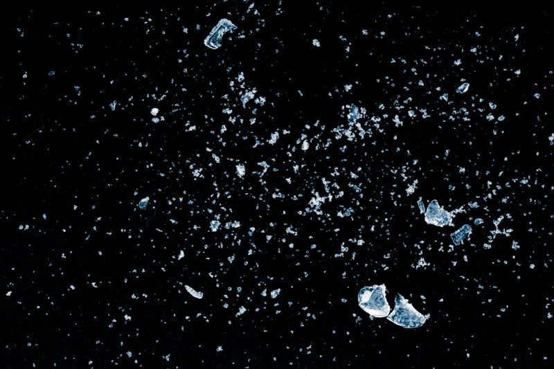Ice, crushed on a black background. Shards and powder of crushed ice.