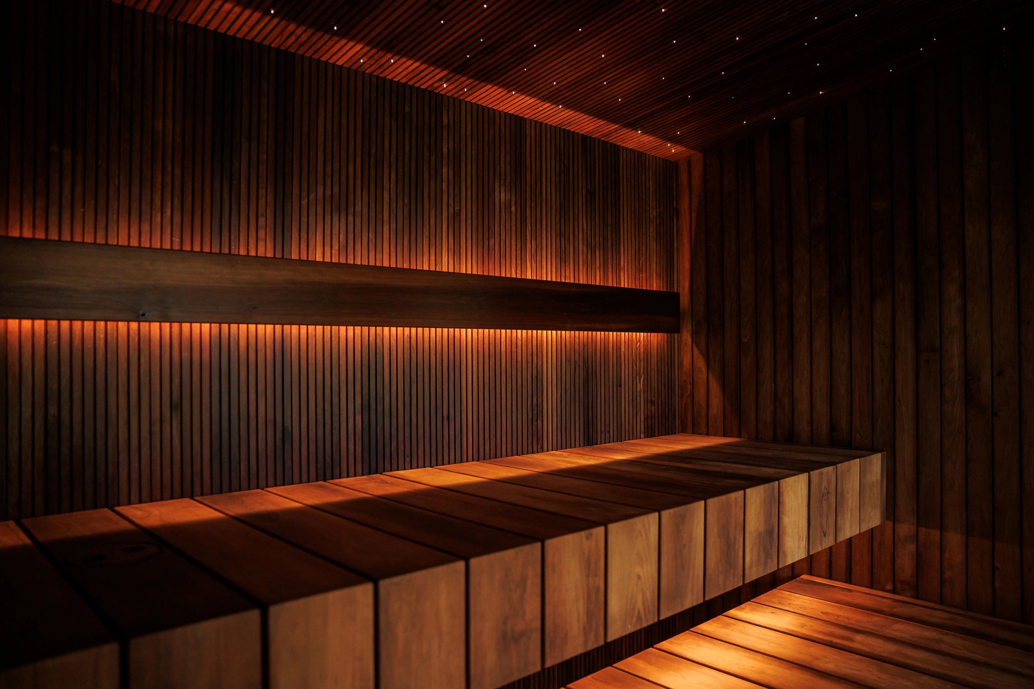Warm-lit wooden sauna interior with tiered benches