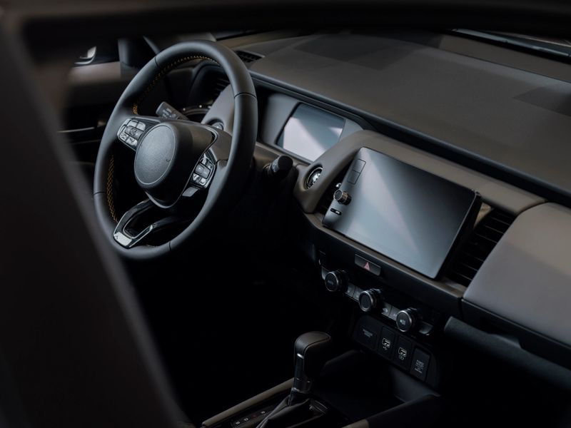 Modern vehicle interior featuring digital display steering wheel and automatic transmission in dark sophisticated design