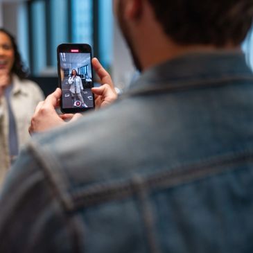 Person recording a woman with a smartphone.