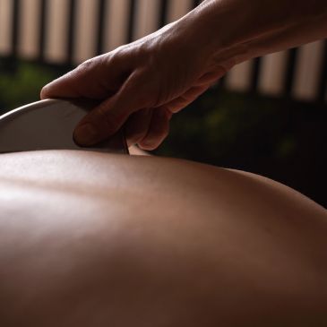 Hand holding a massage tool on a person's back.