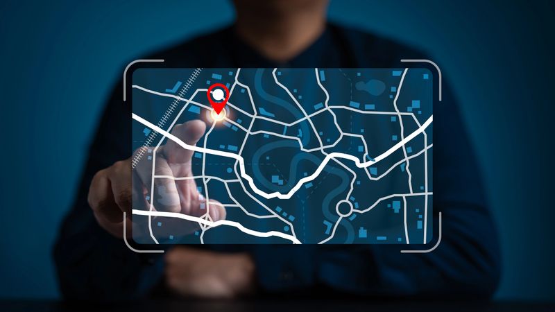 Businessman pointing at a digital map interface with a red location pin. Concept for GPS navigation, logistics tracking, smart city technology, route planning, and geographical search data.