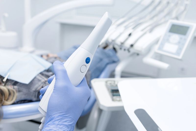 Gloved hand holds intraoral 3D scanner for digital impression and CAD CAM workflow in modern dental office