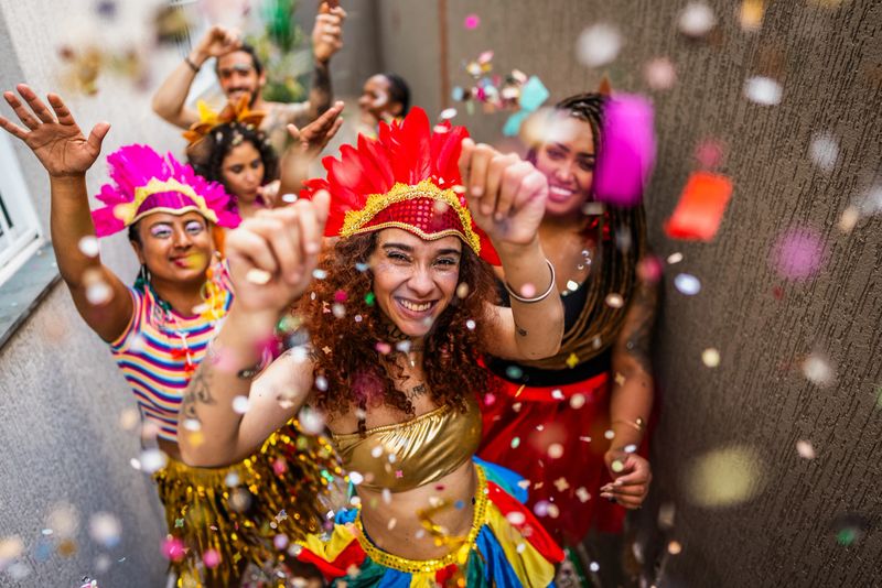 Portrait of a happy young woman dancing enjoying Carnaval with friends at home