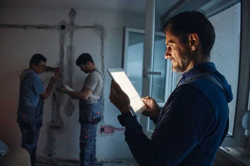 Team of electricians reading plans on a digital tablet at a construction site