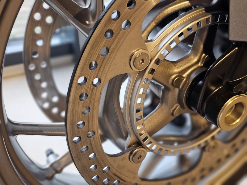 Close view of motorcycle brake disc showing detailed construction and design elements in workshop setting