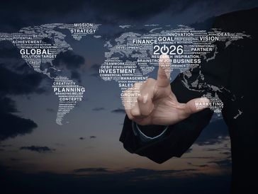 World map made of business and finance words with a hand pointing at 2026.