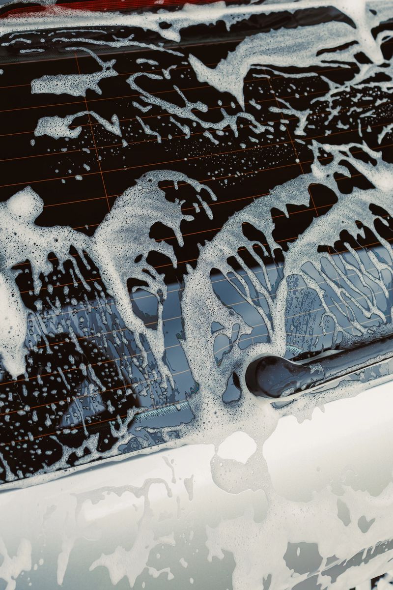 This image offers a closeup view of the luxurious foam covering a car, emphasizing the meticulous process involved in washing and maintaining the vehicles cleanliness and shine