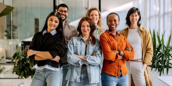Group of six diverse coworkers smiling and posing together.