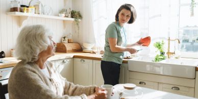 Woman washing dishes while another woman watches.