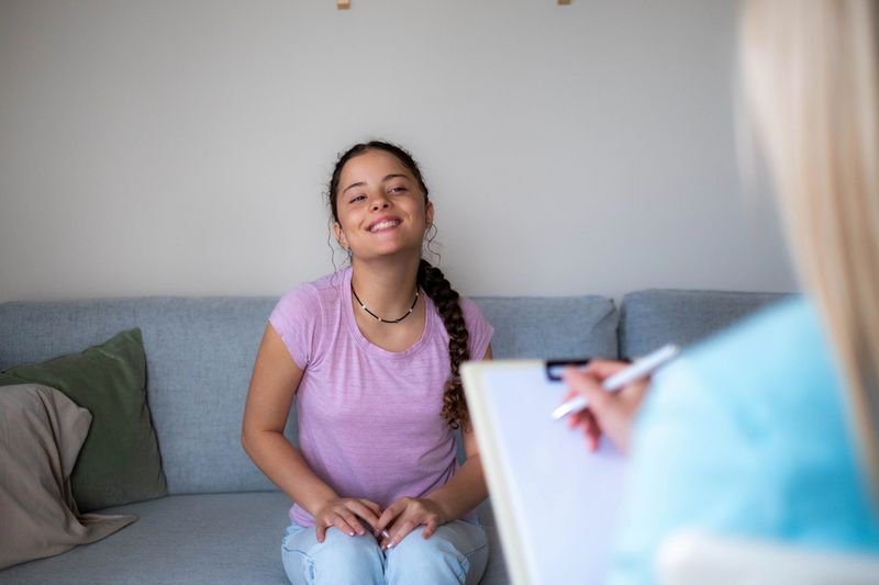 Young woman feeling positive and smiling while talking with a therapist