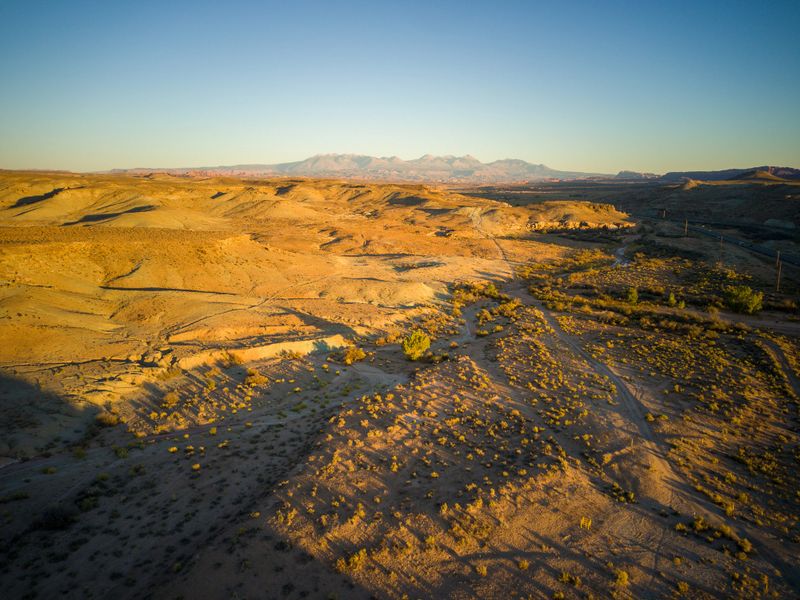 A desert landscape with a road running through it. The road is surrounded by dry grass and rocks