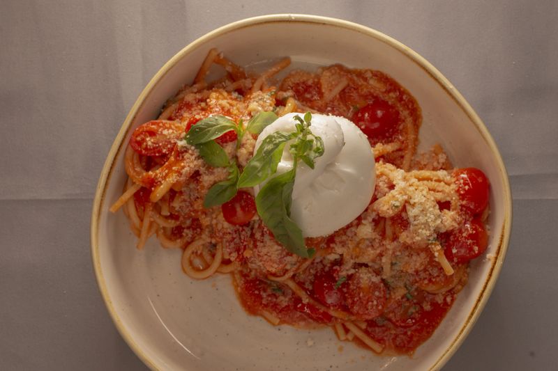 Delicious spaghetti garnished with herbs, Artistic shot of savory pasta covered generously with rich sauce, Vibrant image showcasing tempting pasta dish with herbs and savory sauce coating