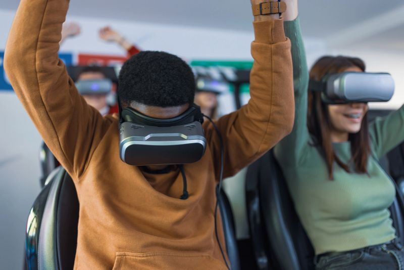 Two people experiencing an immersive VR simulation with headsets, lifting their arms in excitement