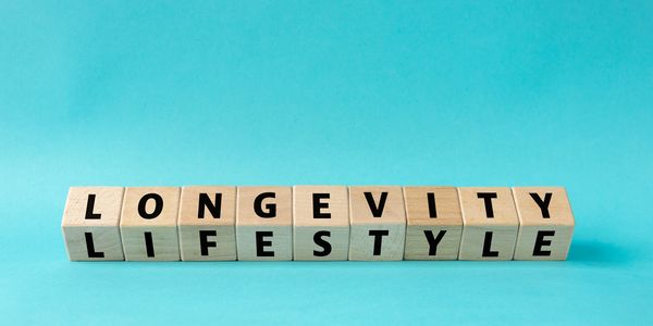 Wooden blocks spelling 'LONGEVITY' and 'LIFESTYLE' on a blue background.