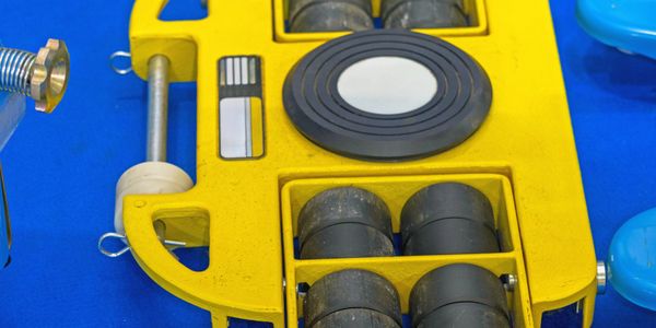 Close-up of a yellow underwater drone with black wheels on blue surface.