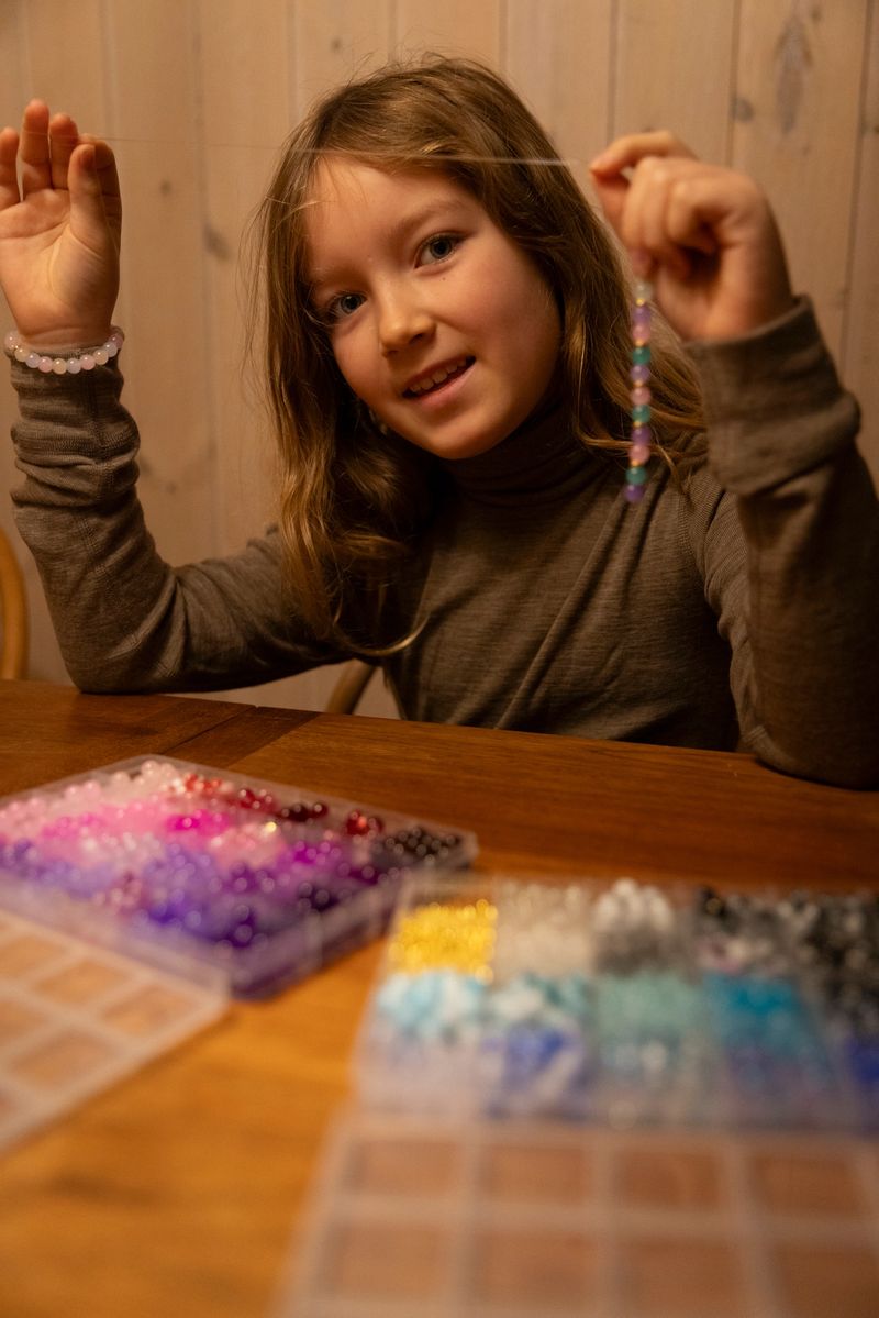 Creative and cute girl  crafting homemade, colourful necklace,  bracelet and wristband.