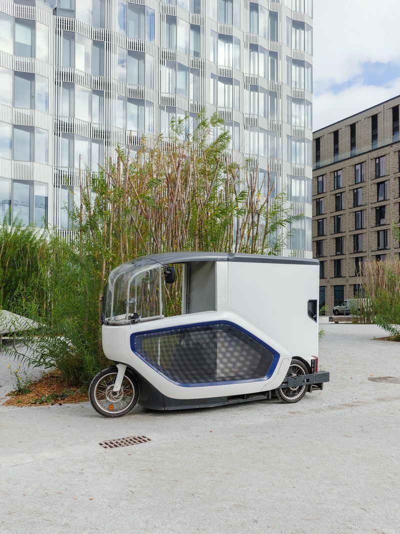 Modern electric cargo bike parked outdoors near an office building, designed for sustainable urban delivery transport