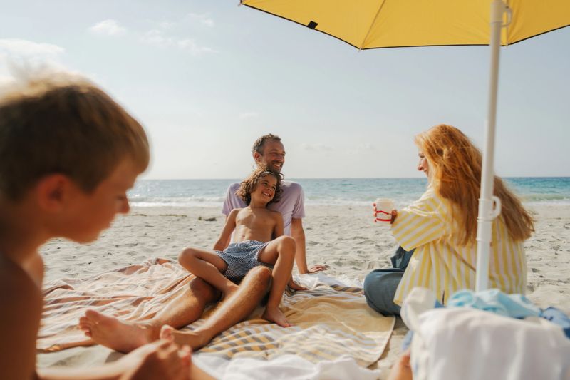 Photo of a young family, having a picnic on the beach by the ocean