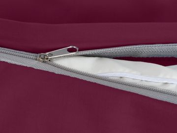 Close-up of a partially unzipped maroon fabric zipper revealing white padding inside.