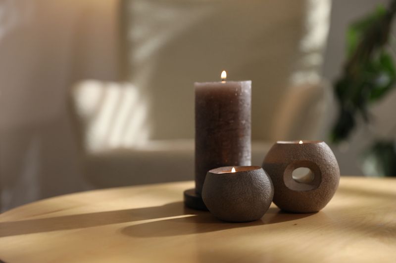 Burning candles on wooden table indoors, closeup with space for text