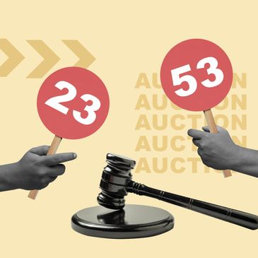 Two hands hold auction paddles numbered 23 and 53 beside a judge's gavel.