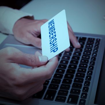 Person holding a membership card over a laptop keyboard.