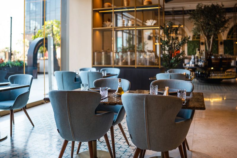 Contemporary dining space featuring stylish blue chairs and refined table settings in a modern fine dining restaurant, showcasing a chic and spacious interior design.