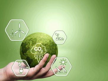 Hand holding a green globe with renewable energy icons.