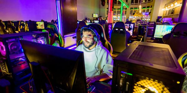 Man gaming with headphones in a vibrant gaming setup.