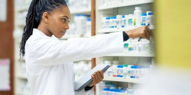 Pharmacist selecting medication from shelves.
