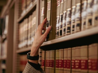Person reaching for a law book on a shelf.