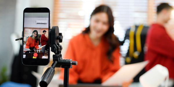 Woman recording video on smartphone in office.