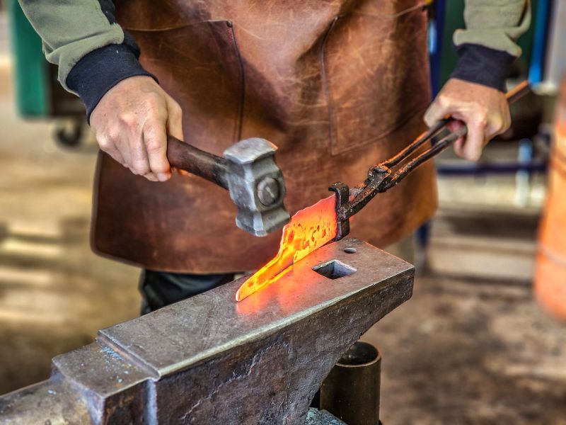 Action shot of a worker completing a blacksmithing job.